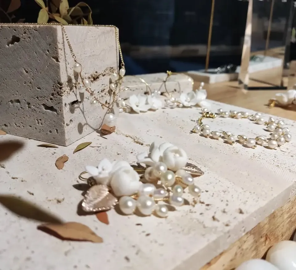 Pearl and white flower earrings and pearl necklaces displayed on travertine